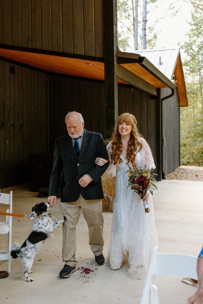 bride walking down the aisle with her dad at rental cabin for elopement in Broken Bow