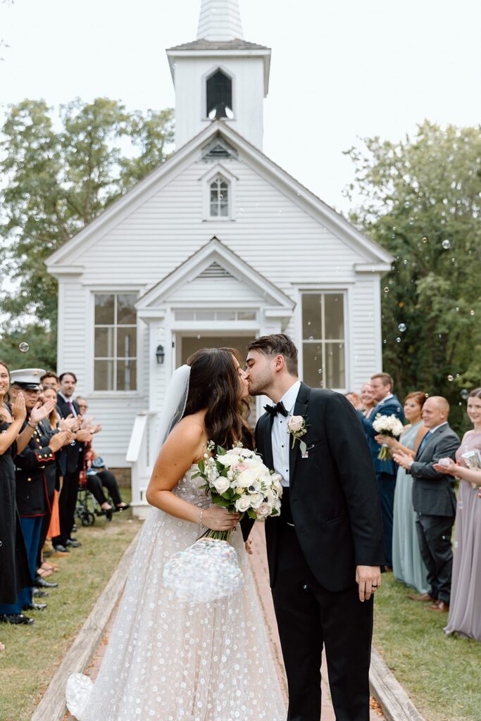 Couple kissing as the are leaving the chapel with bubble exit 