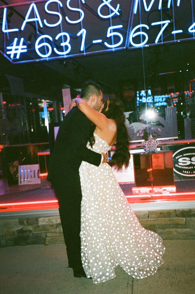 Film portrait of bride and groom in front of neon sign 