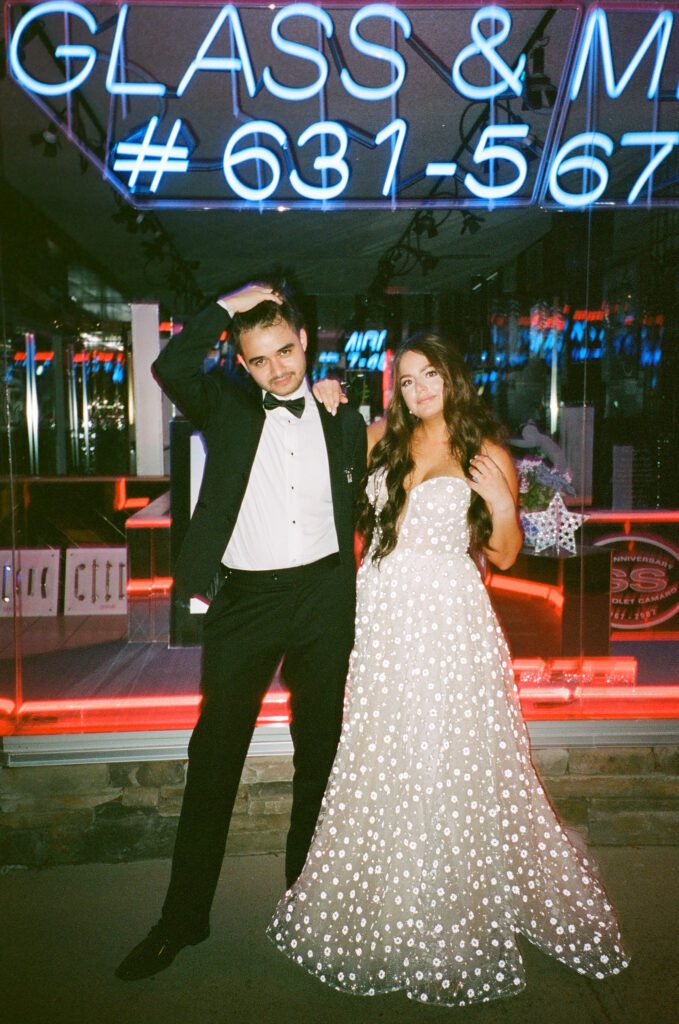 Film portrait of bride and groom in front of neon sign in New York