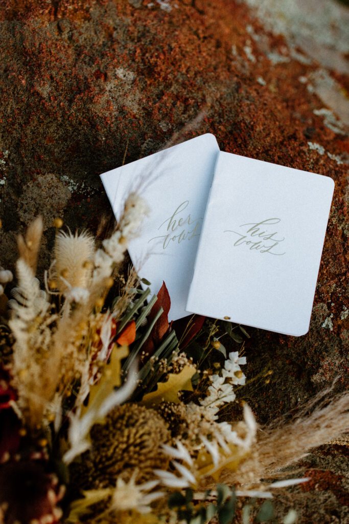 Detail photo of vow books and boho bouquet of flowers