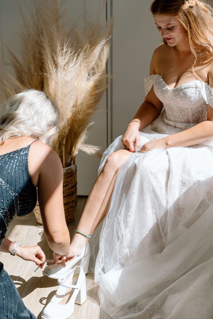 mother of the bride putting on brides shoes 