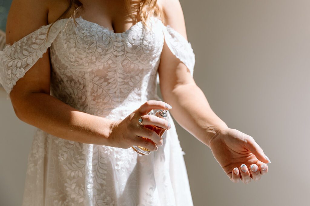 bride putting perfume on her arm 