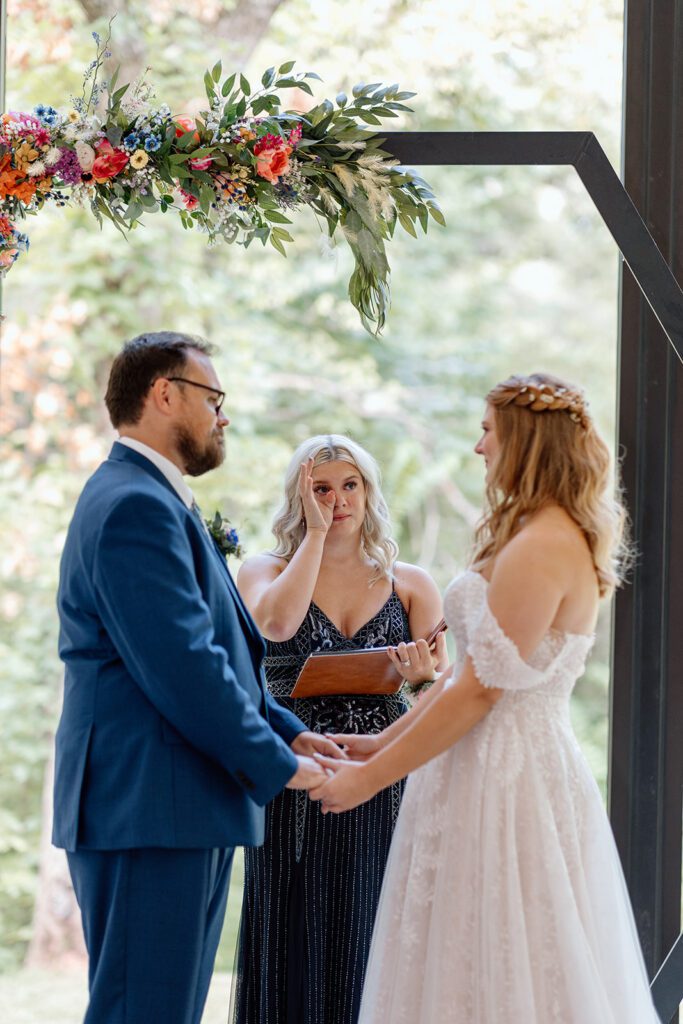 bride and groom sharing vows with officiant crying 