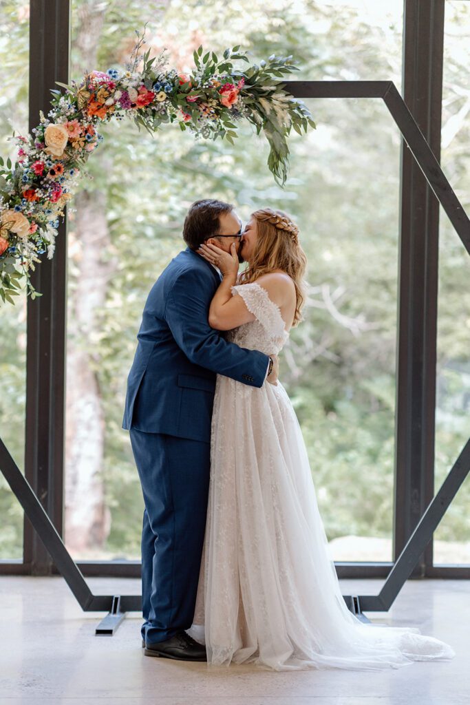 bride and groom kissing under ceremony hexagon arch 