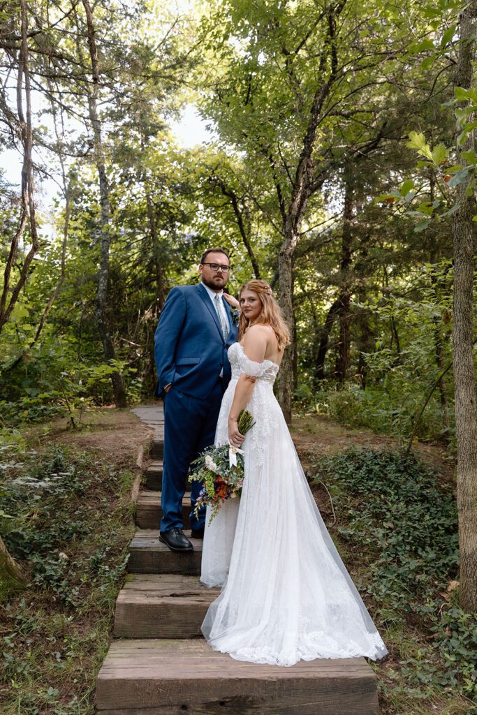 bride and groom on steps in woods