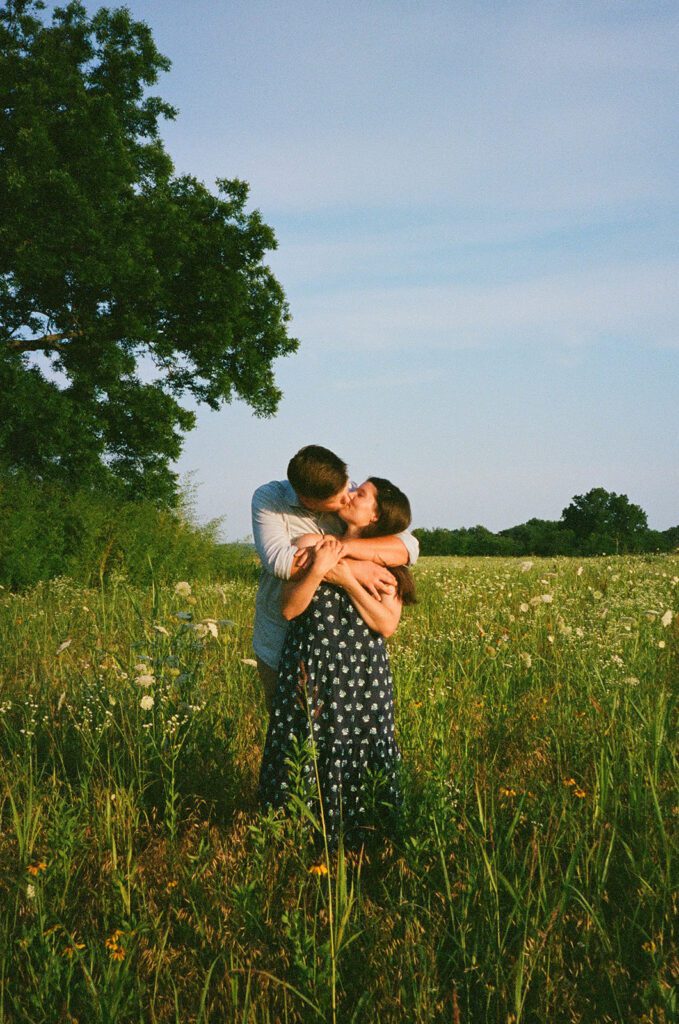 couple kissing golden hour wildflower field 