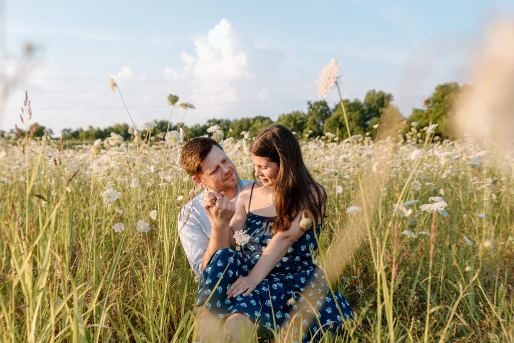 couple sitting in queen's Anne lace field wildflower engagement session 