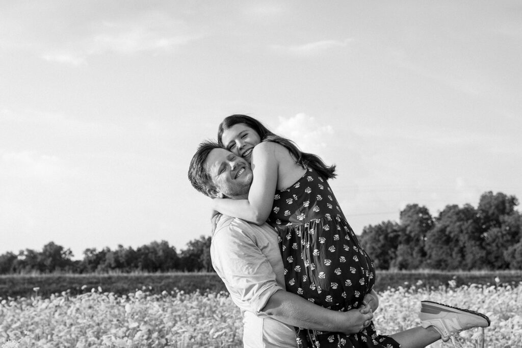 man carrying woman in wildflower field 