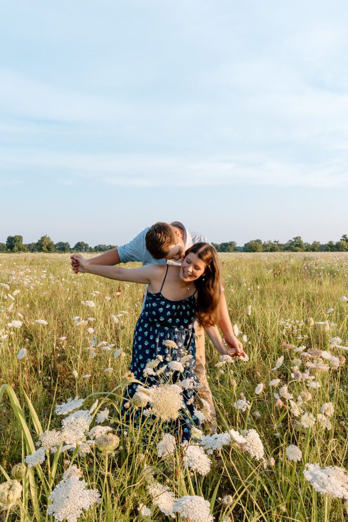 couple in wildflower engagement session holding hands in field