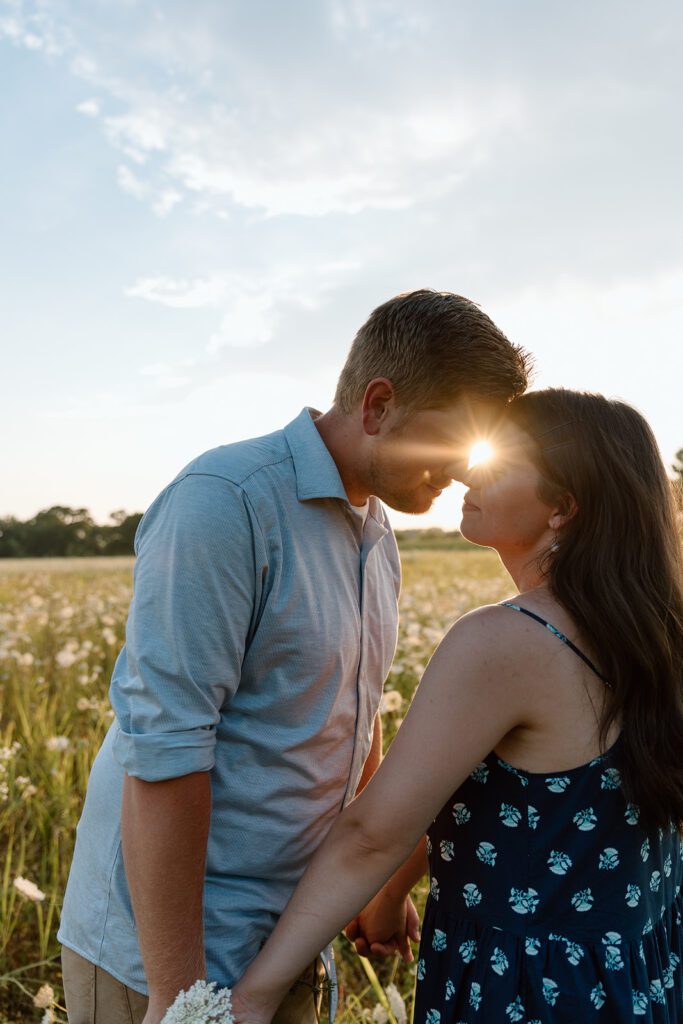 couple in field with sun filtering in-between them wildflower engagement session