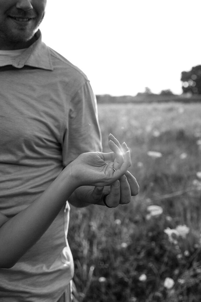 engagement shot of couples hand sunlight filtering in black and white 