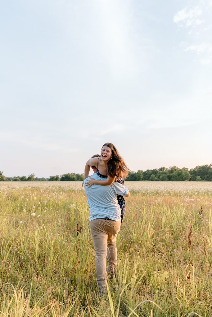 man runs with women laughing over his shoulder engagement shot 