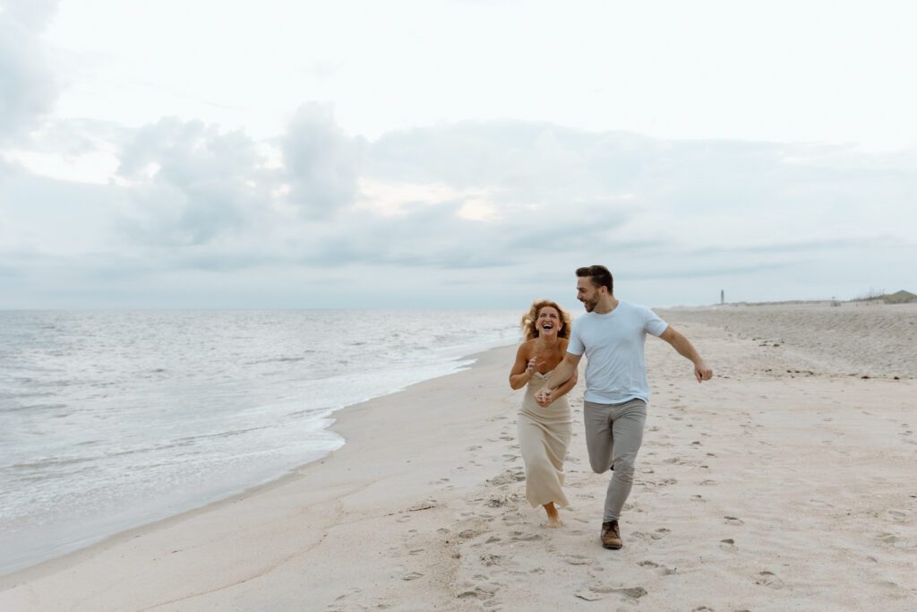 couple running on sandy beach at sunset 