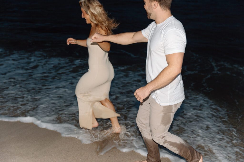 couple running through the waves in the dark 