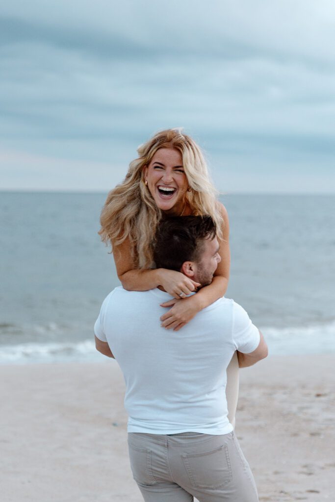 women laughing at the beach while being carried 