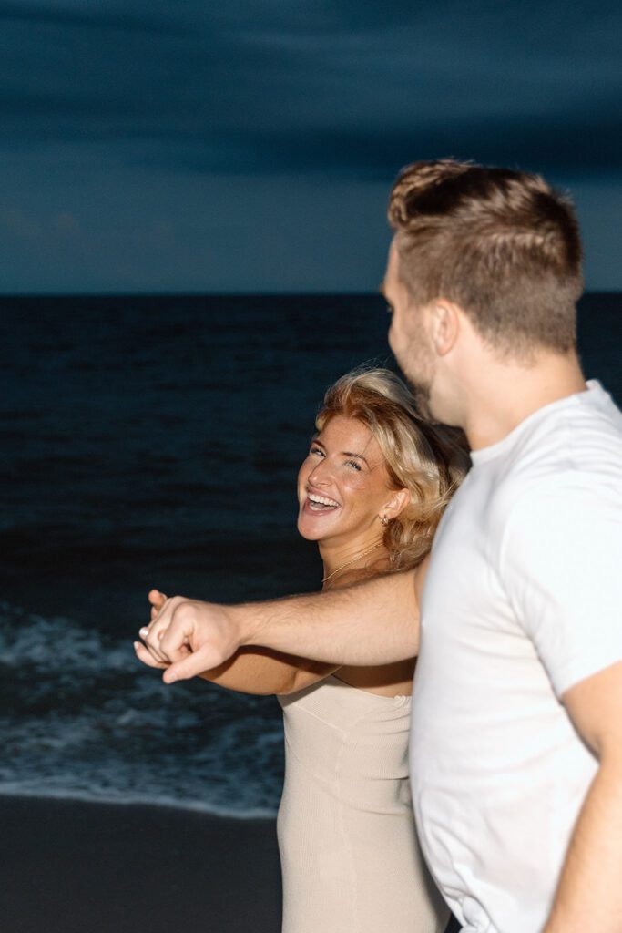 couple walking and dancing on the beach in the dark 