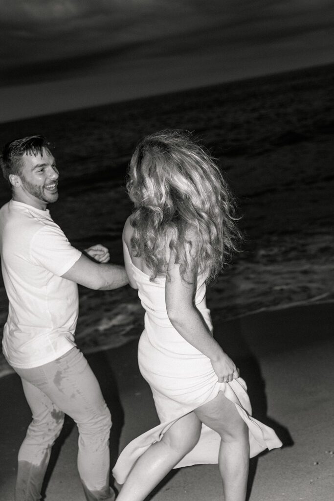 black and white of couple walking in the waves 