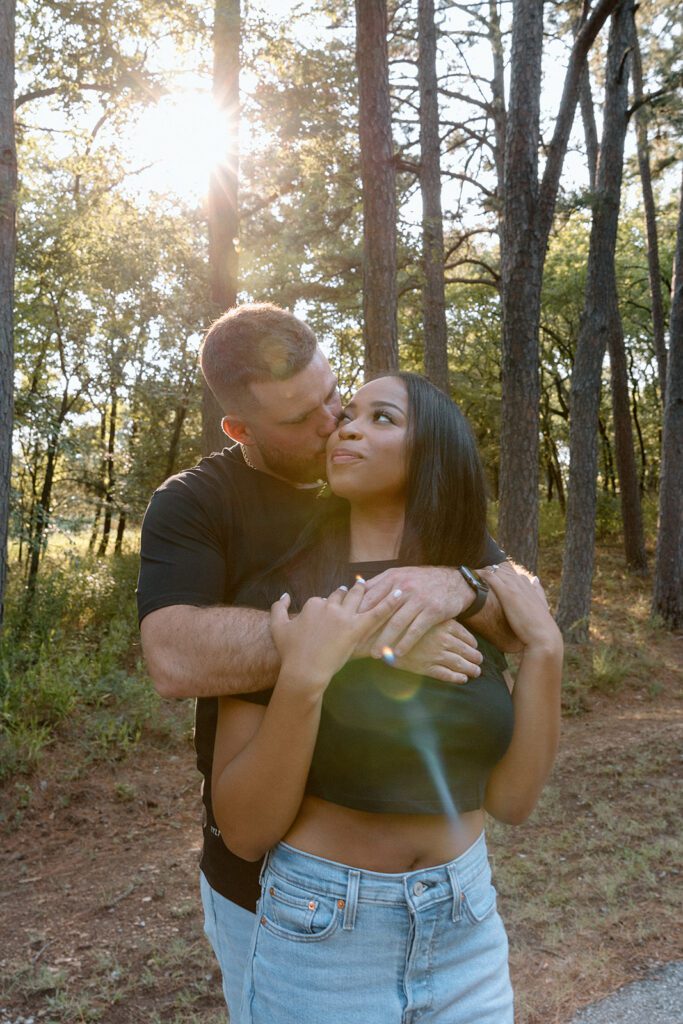 interracial couple embrace in the forest for engagement shot