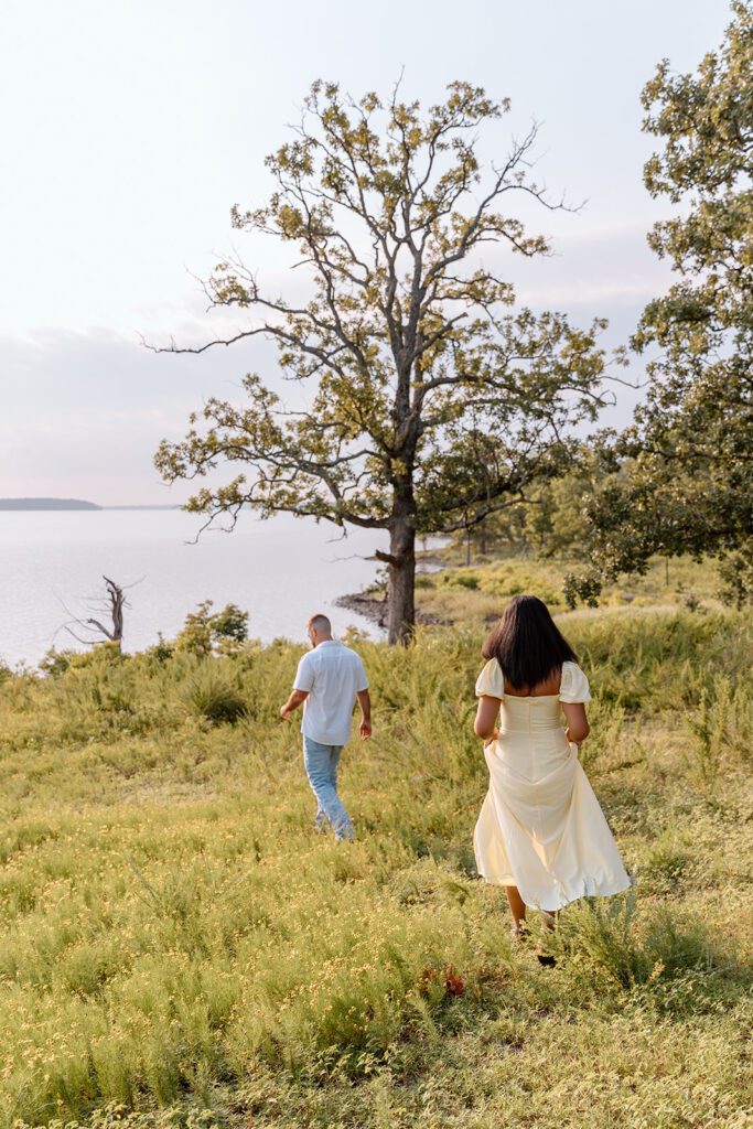 man walks in prairie with woman following toward lake 