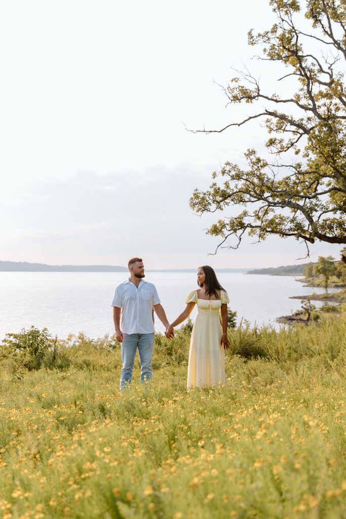 couple in prairie looking at each other lake behind 