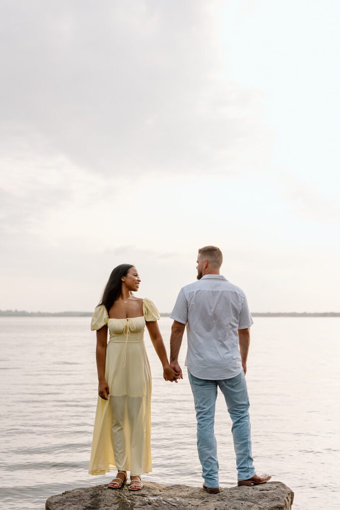 interracial couple on a rock in lake holding hands