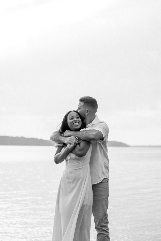 man hugs woman from behind on lake 