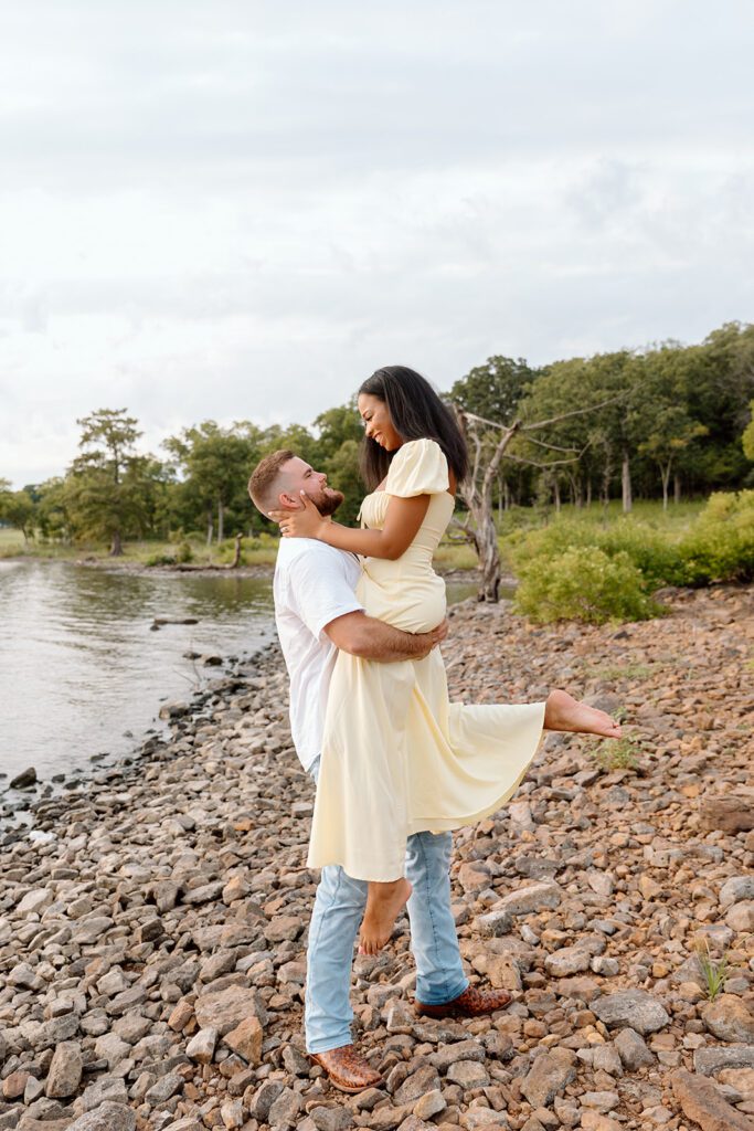 man carries women on lake shore 