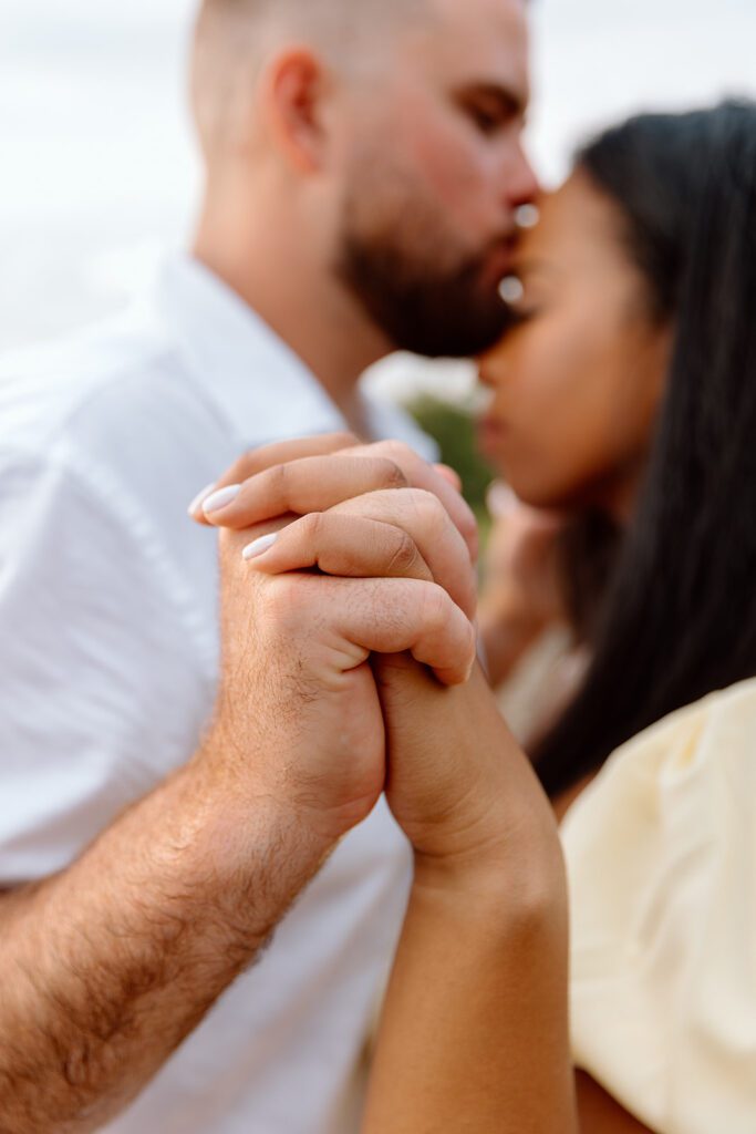 man kisses woman's forehead and they hold hands 