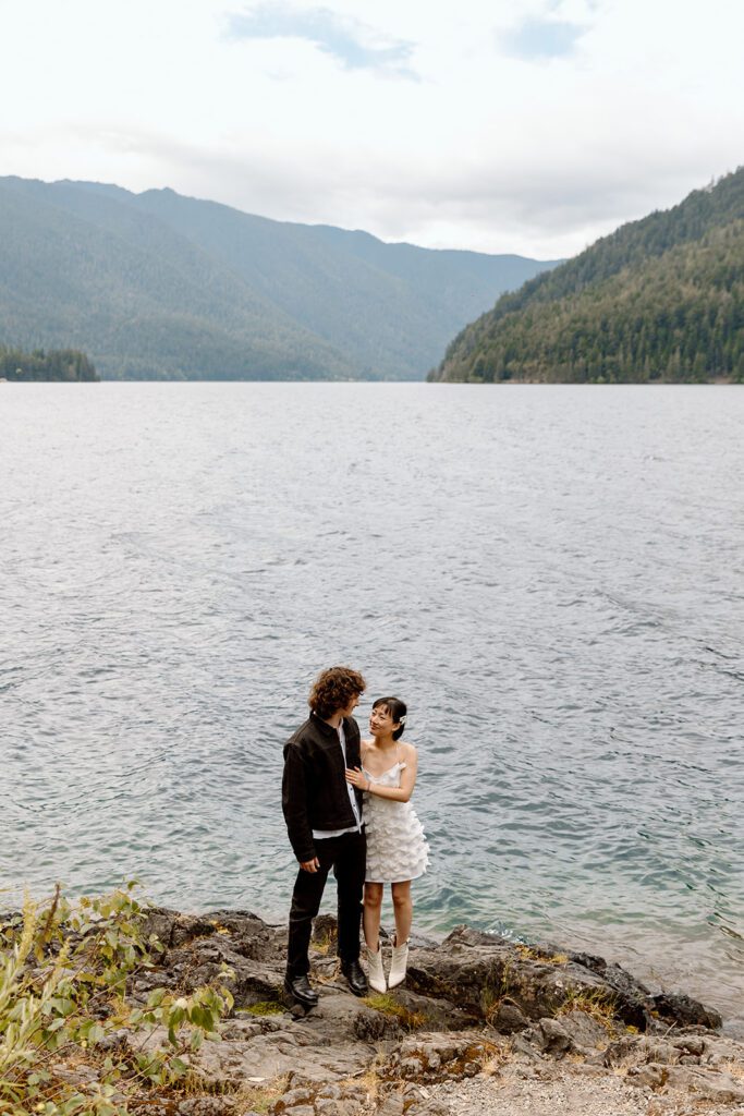 couple looking at each other on PNW beach with Mountain background 