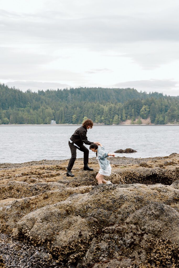 couple help each other over rocks at beach in Olympic National Park PNW 