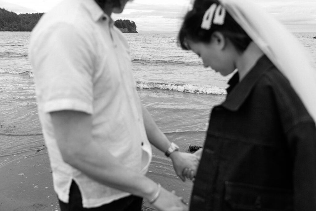 man and women holding hands by beach black and white PNW