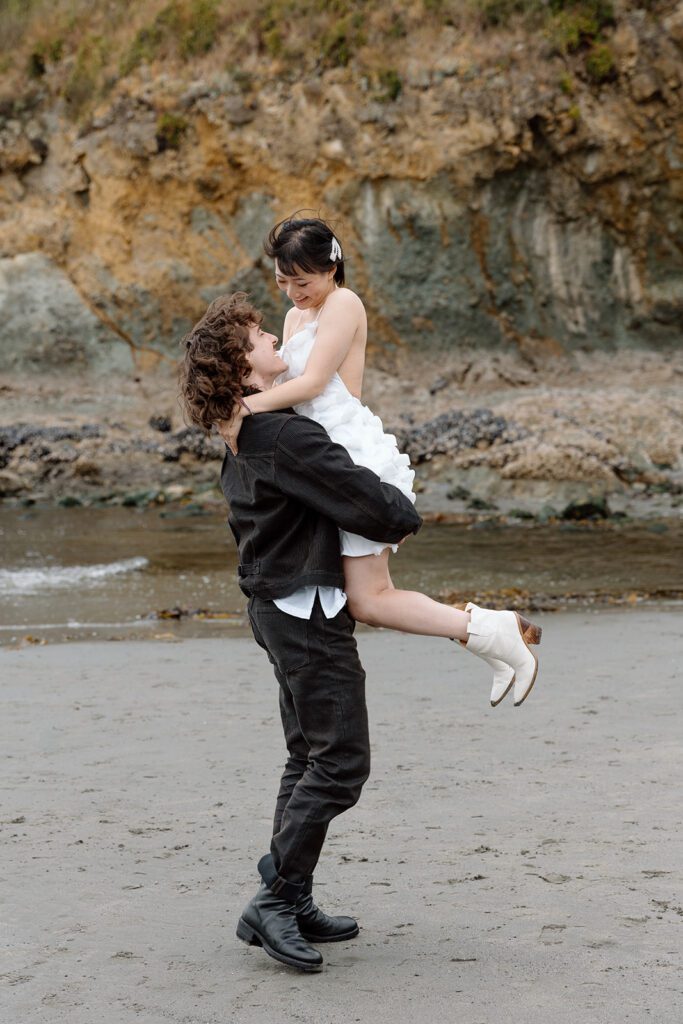 groom carries bride at engagement shoot PNW Olympic National Park beach 
