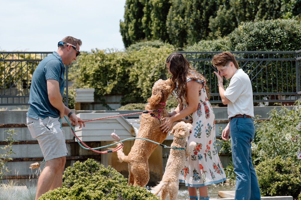 couple embraces their dogs while woman wipes tears 