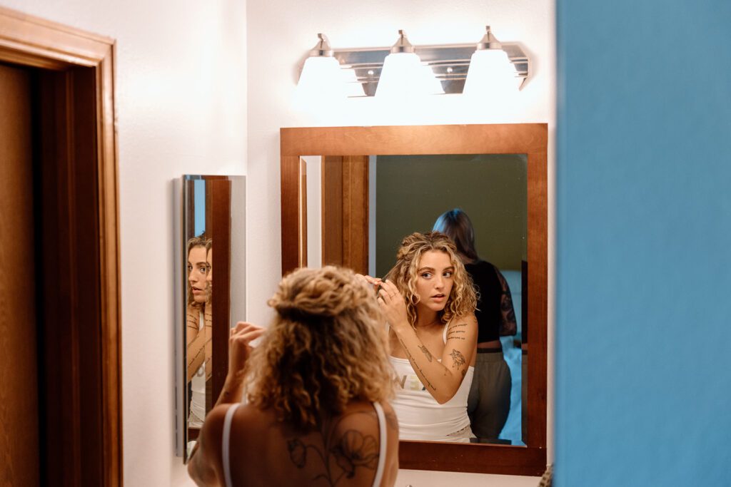 curly haired bride getting ready in mirror 