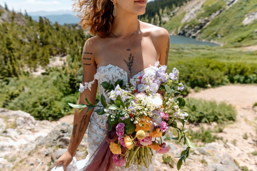 tattooed bride in lace sweetheart dress with cold shoulder straps and wildflower bouqet 