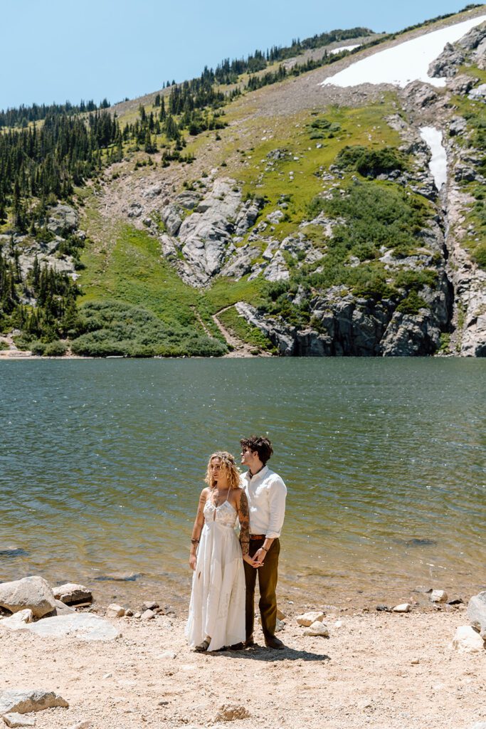bride and groom pose in front of glacier lake 