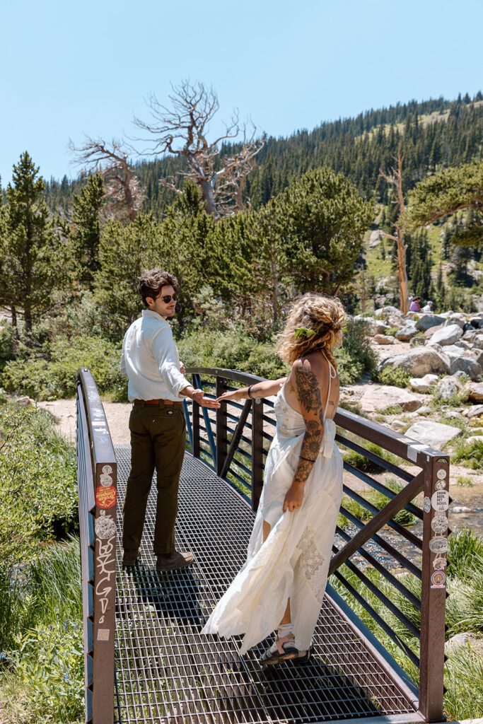 groom leads boho bride on bridge 