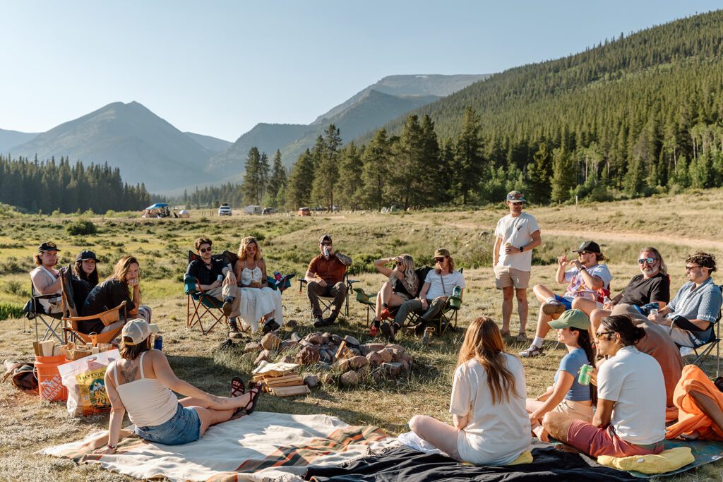 bride and groom with guests around a campfire at elopement reception in Guanella Pass, Colorado