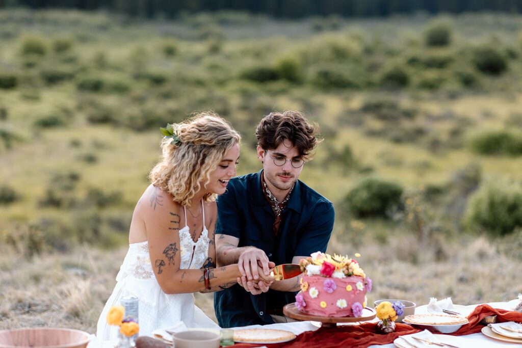 Tattooed Bride and groom cut wedding cake at elopement in Colorado 