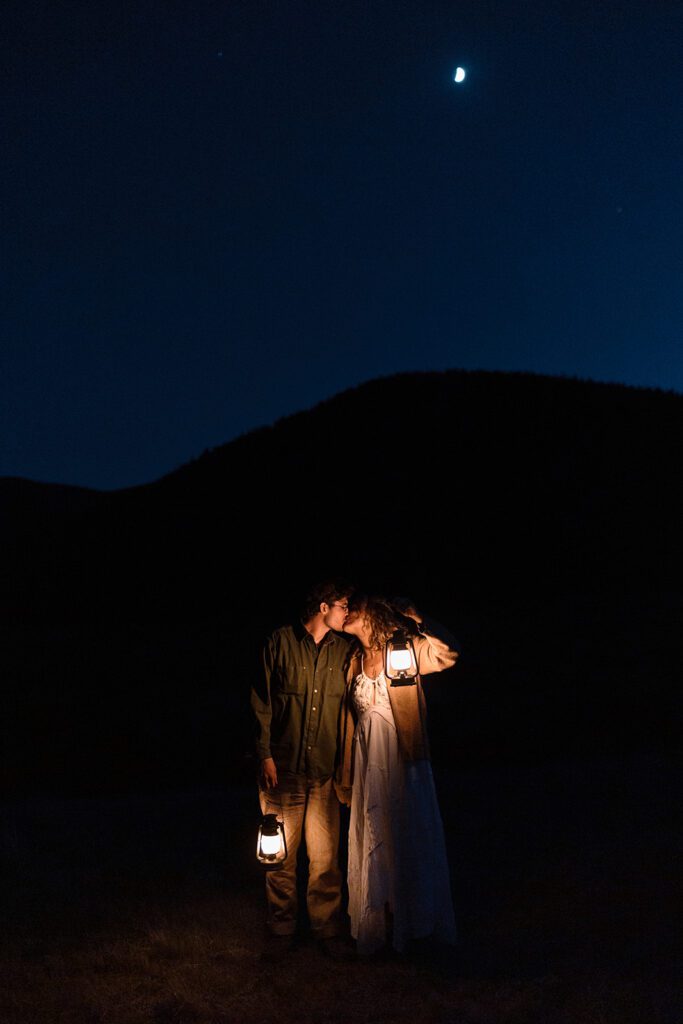 bride and groom walk in the dark with lanterns and kiss 