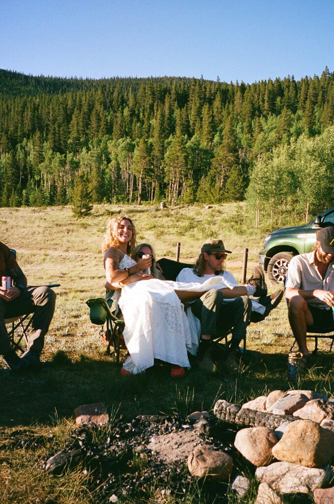bride with friends around campsite bonfire during reception 