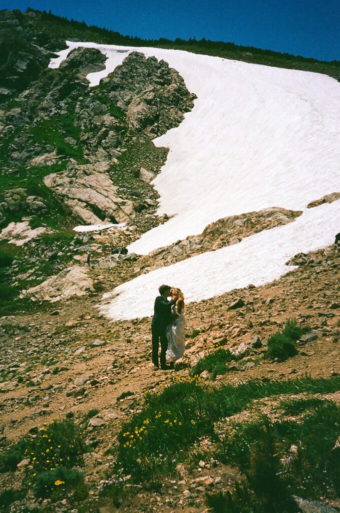 bride and groom kiss in front of glacier 