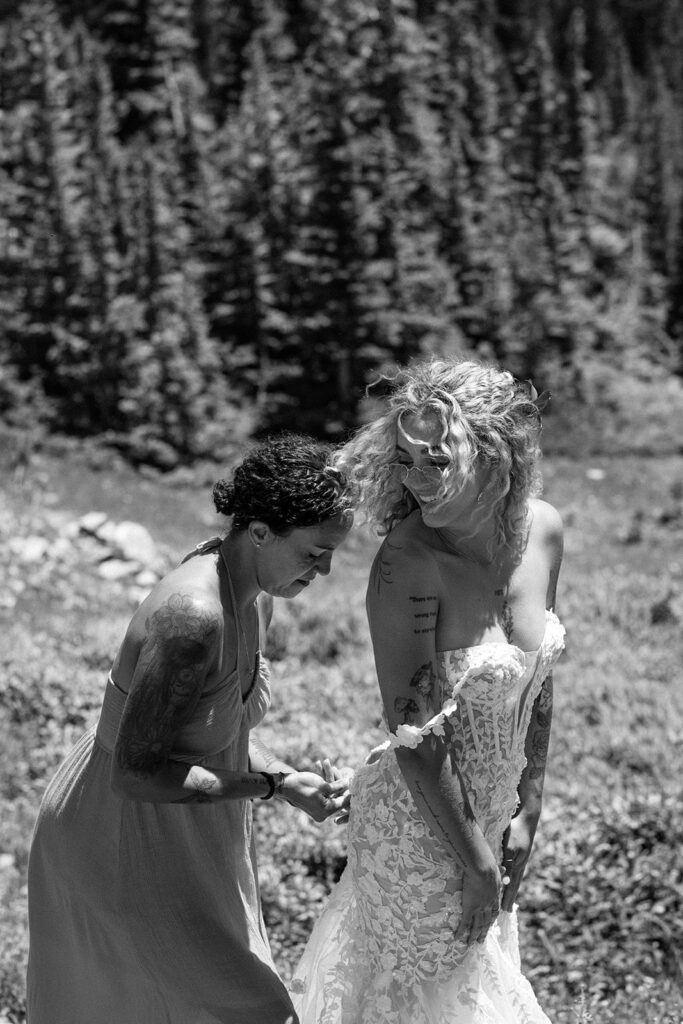 mother of the bride zips up dress at outdoor camping elopement in St, Mary's Glacier, Colorado 