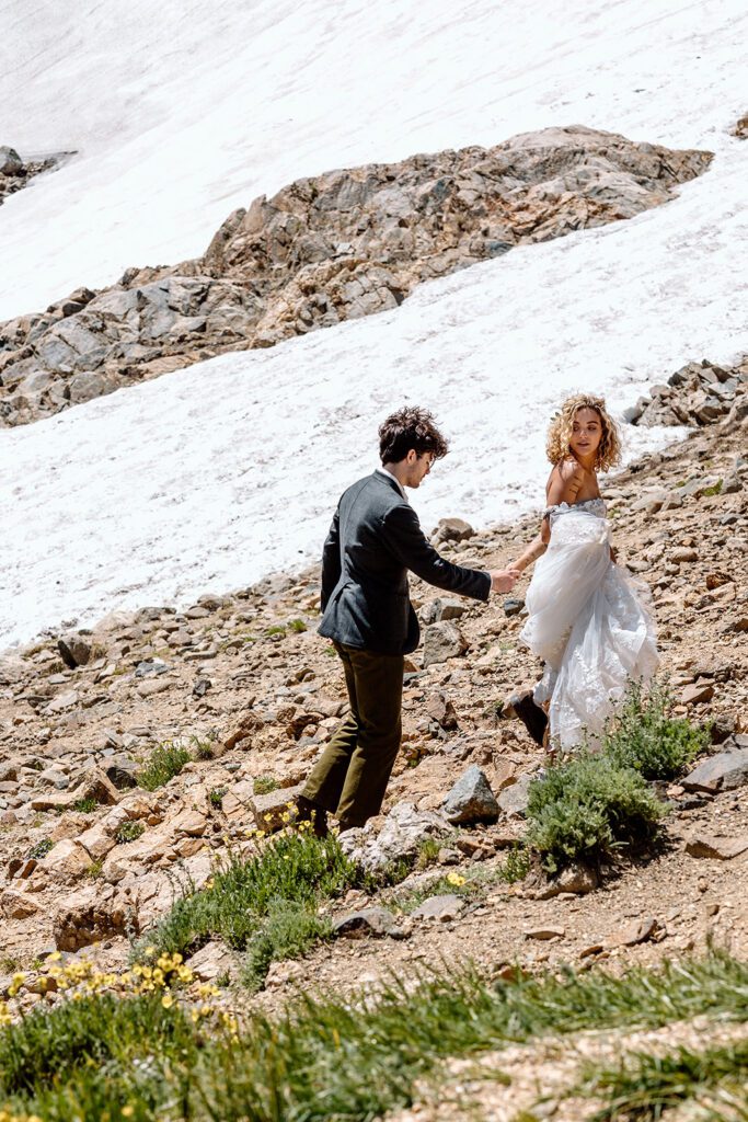bride leads groom up glacier during elopement session 