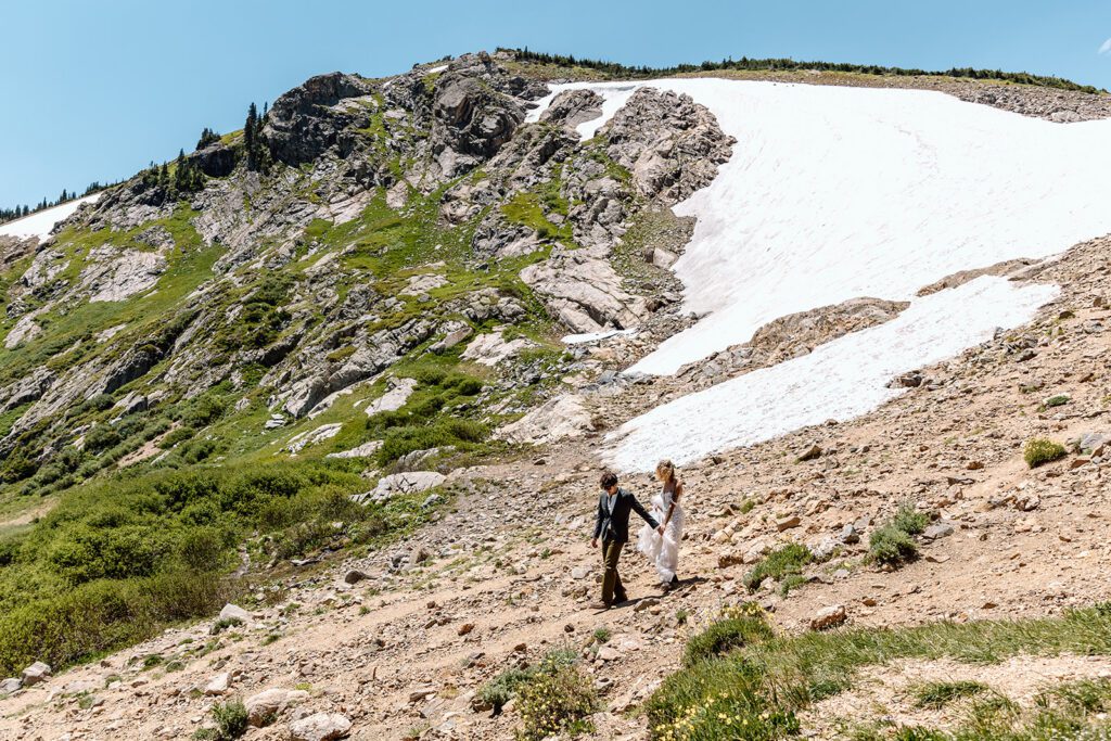 groom leads bride down mountain after elopement in Colorado 