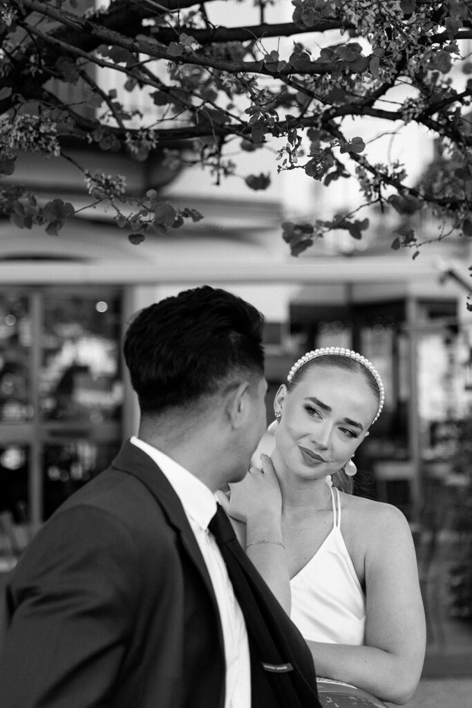 black and white of bride looking at groom under spring blooms