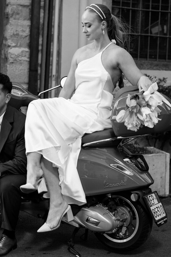black and white of bride sidesaddle on vespa in italian elopement 