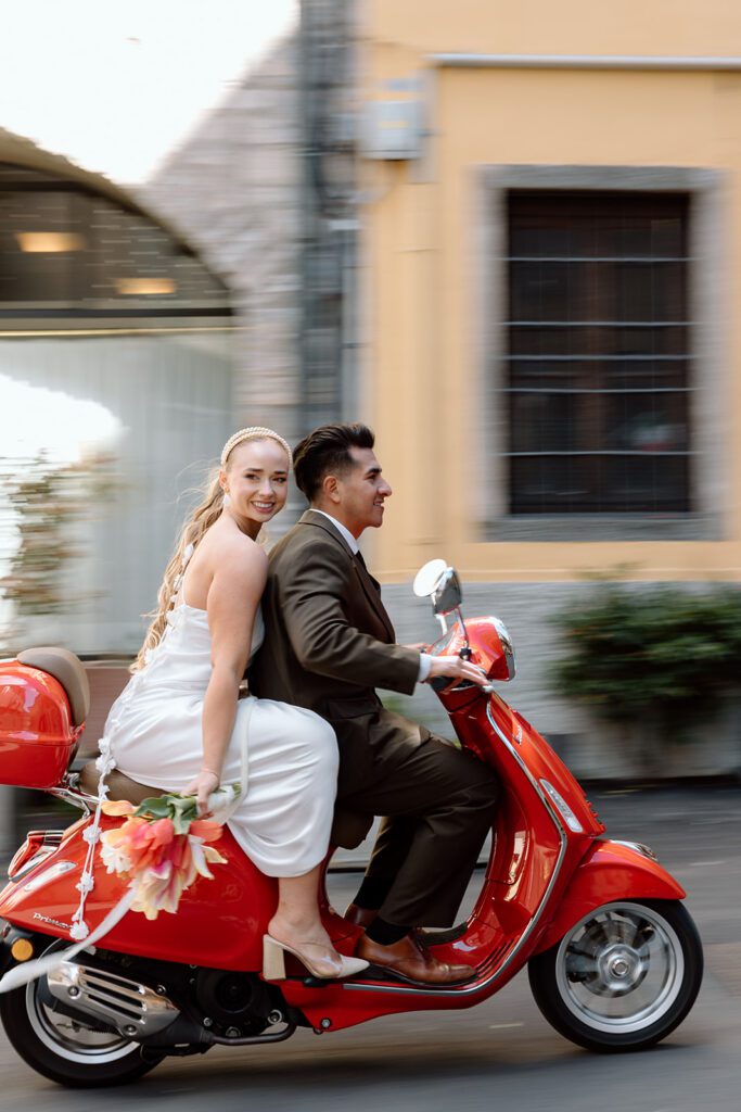bride smiles and looks back from red vespa italian elopement 