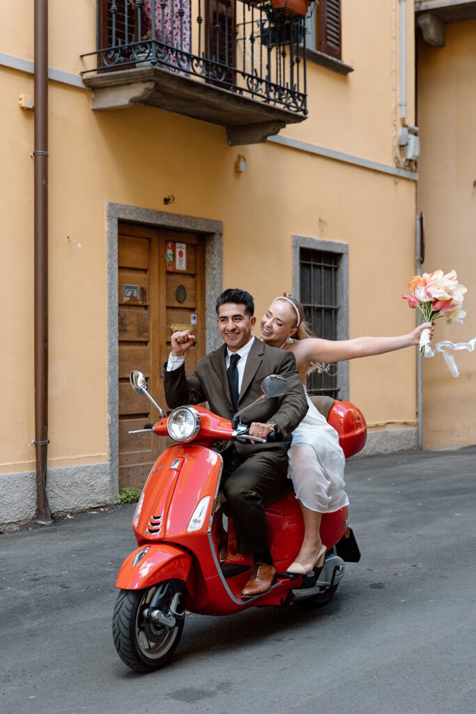 groom fist pumps and bride cheers on red vespa 
